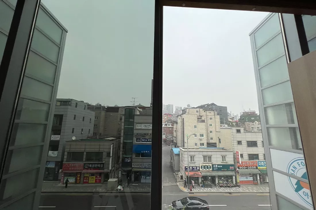 필름 시공 전 통유리창 너머로 보이는 바깥 거리 풍경